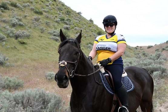 Woman on horseback with yellow and white jersey that says "Ranger".