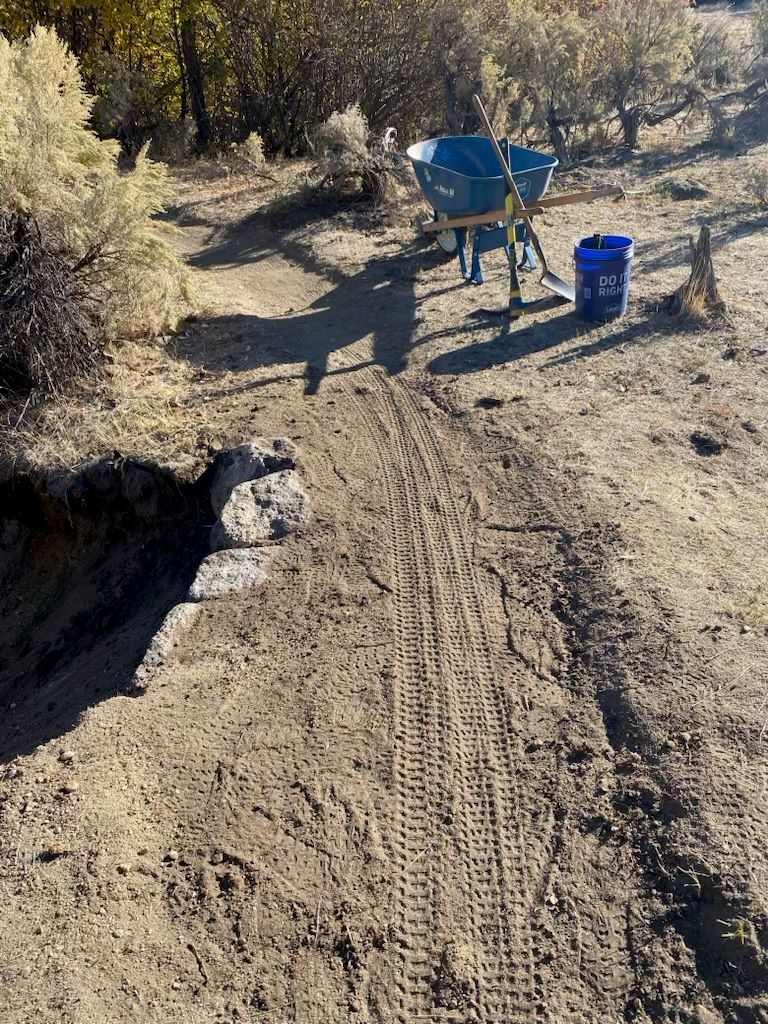 A wheelbarrow used for repair is on the side of Peggy's Trail in the morning.